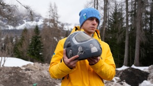 Ukrainian skeleton athlete Vladyslav Heraskevych holds his crash helmet as he stands outside the sliding center at the 2026 Winter Olympics, in Cortina d'Ampezzo, Italy, Thursday.