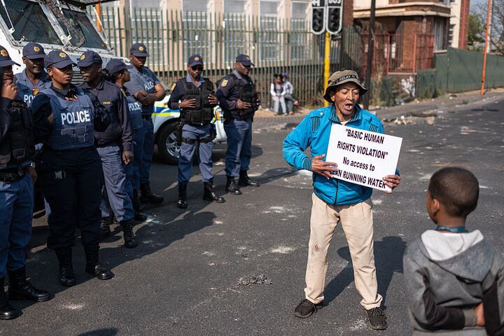 Residents hold placards and chant as they gather during a protest over water cuts in Johannesburg.