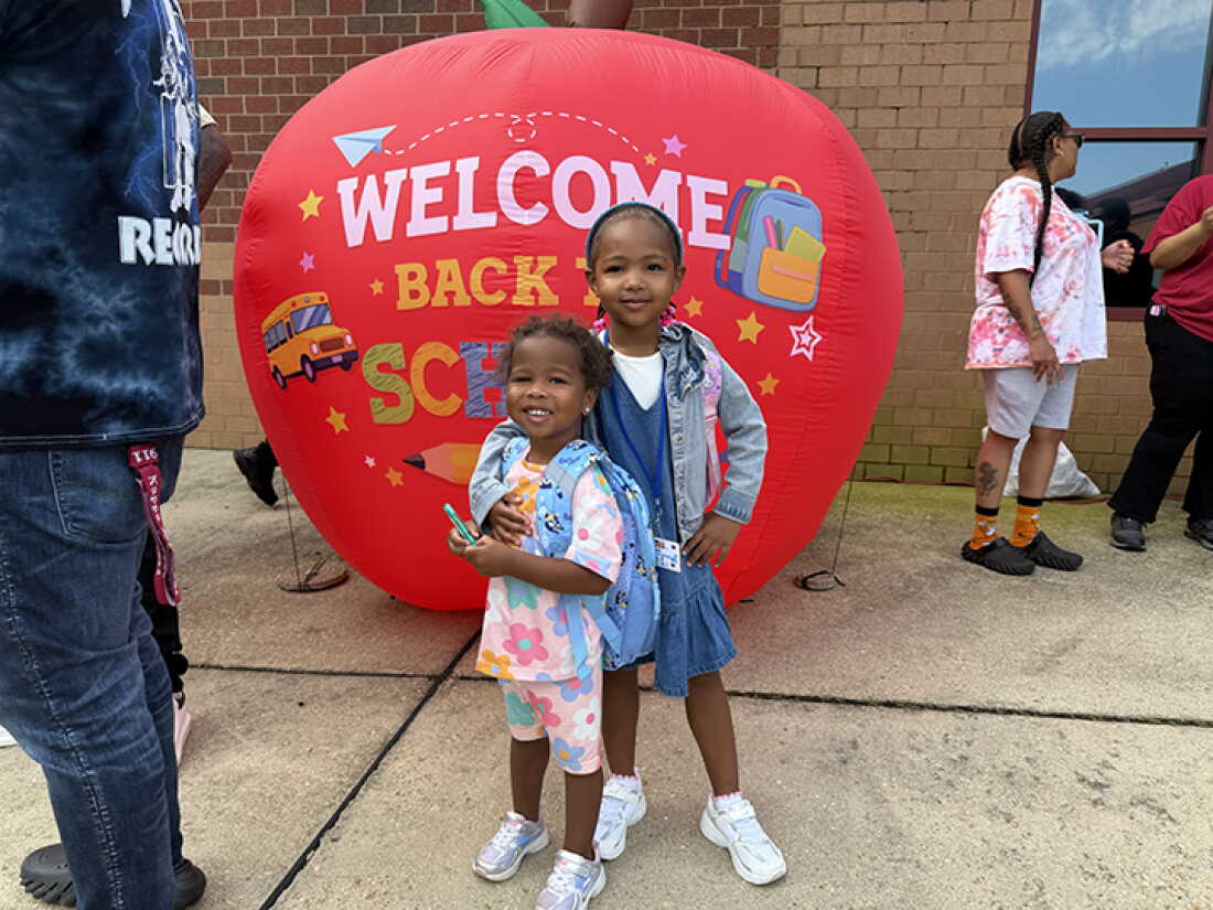 4-year-old Olivia Person stands outside Charles City Elementary on her first day of school with her 2-year-old sister Aria.