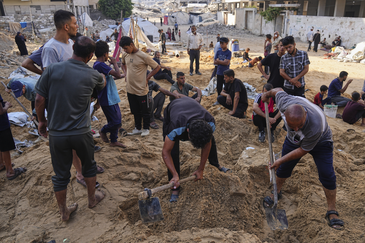 Palestinians dig through sand looking for belongings after an Israeli strike hit a displacement tent camp in Gaza City, Saturday, June 28, 2025.