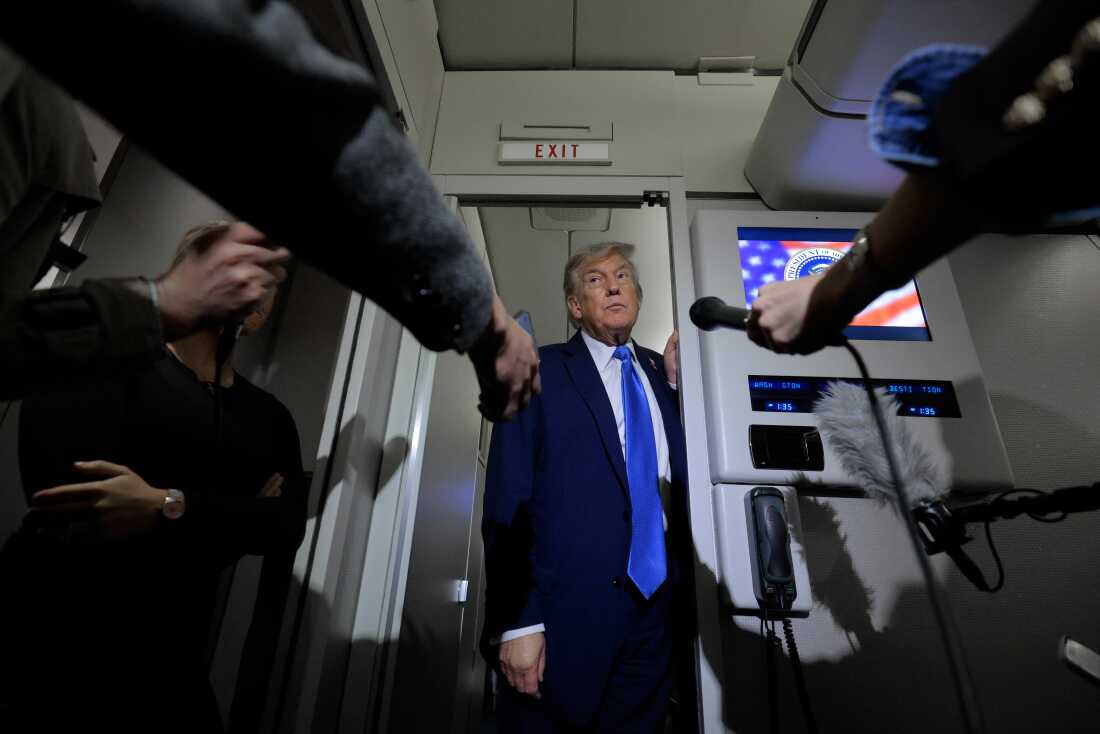 President Donald Trump talks to reporters on board Air Force One on Monday.