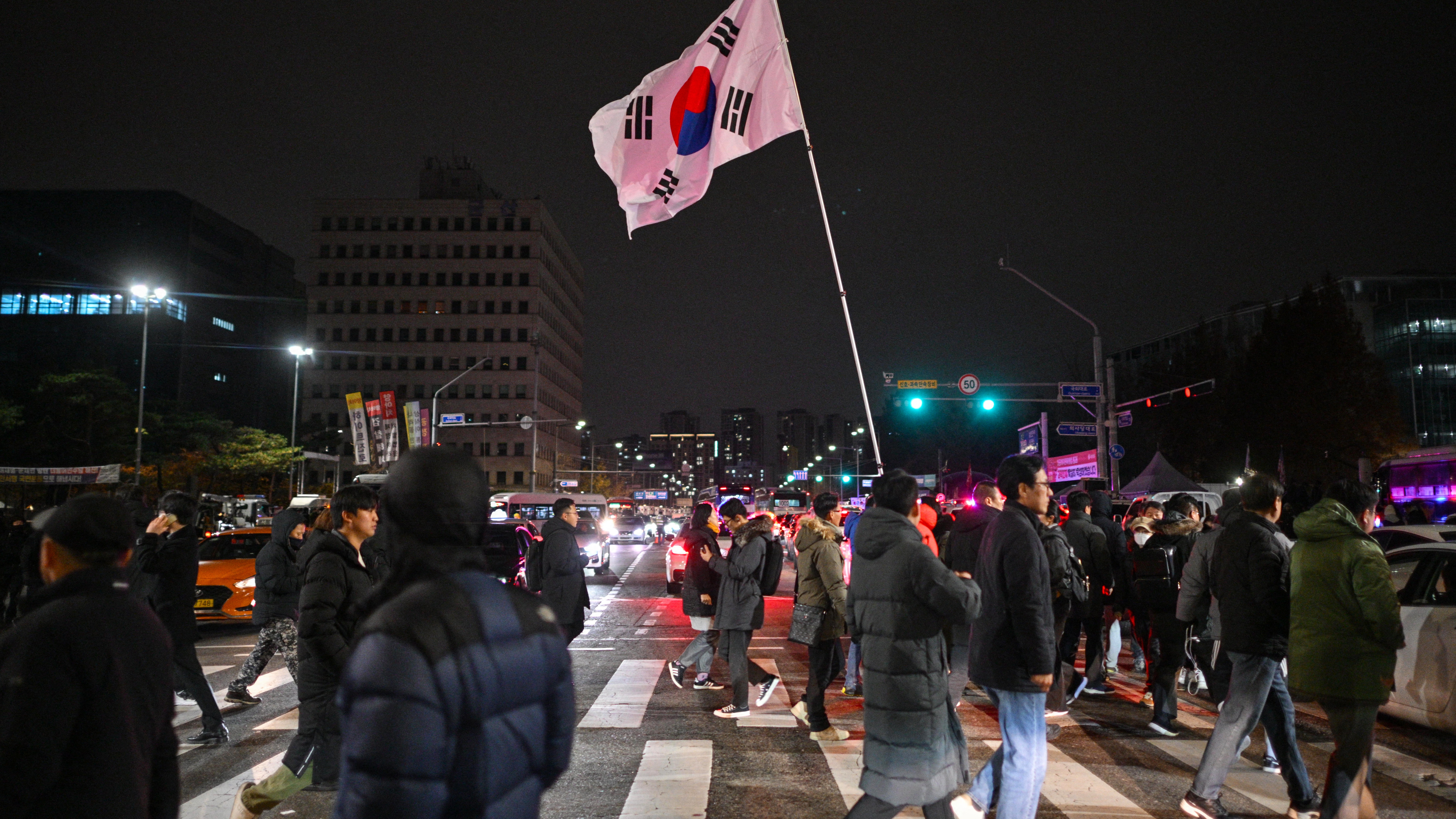 A man holds the South Korea flag outside the National Assembly in Seoul on December 4, 2024, after President Yoon Suk Yeol declared emergency martial law.