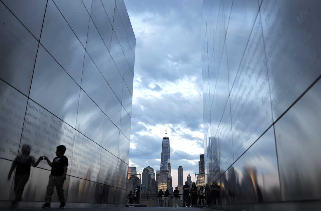 A child walks between the twin parallel walls of Empty Sky, the 9/11 memorial in Jersey City, New Jersey, on August 23. In the background are One World Trade Center and other tall buildings in Lower Manhattan.