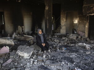Ihsan Yaghi stands inside her heavily damaged home. She was displaced to Beirut's southern suburbs but returned to her village of Zawtar al-Gharbieh every day. She has six daughters, and her husband is retired.
