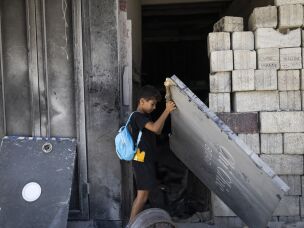 A boy removes a metal sheet to enter the old market of Nabatiyeh, heavily damaged by the war. The city is full of destroyed and damaged buildings after nearly all of its 80,000 residents were displaced by Israeli bombardments and evacuation orders.