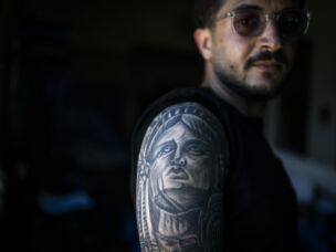 Ali Rida, a member of the Nabatiyeh paramedic team, poses for a portrait. He has a full-sleeve tattoo depicting characters from the movie <em>The Godfather</em> and the Statue of Liberty.