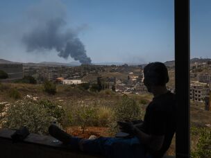 A member of the paramedic team watches a column of smoke rise after an Israeli strike in Nabatiyeh, Lebanon.