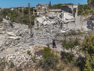 On July 28, 2026, a Lebanese woman walks through a devastated landscape in Zawtar al-Gharbieh, southern Lebanon, following the withdrawal of Israeli forces. Lebanese residents were forced to leave their homes for months but are now slowly returning to their devastated town.