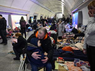 Sergyi Badylevych kisses his young child as his wife, Natalia Badylevych, stands nearby in an underground metro station used as bomb shelter in Kyiv on March 2, 2022.