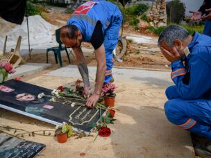 Mohammed Suleiman (right), a veteran Lebanese paramedic and co-founder of the Nabatiyeh Ambulance Service, mourns at the flower-festooned grave of his 16-year-old son Joud, on April 28, in Nabatiyeh, Lebanon. Joud was a rescue team assistant who was killed by an Israeli drone while riding a motorcycle with team paramedic Ali Jaber, both men in uniform, on March 24.