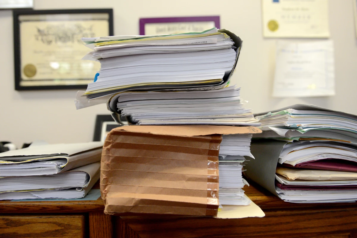 Folders containing documents related to immigration cases are piled on a table in the office of Stephen Born, Esq. on July 31, 2025 in Everett, Mass.