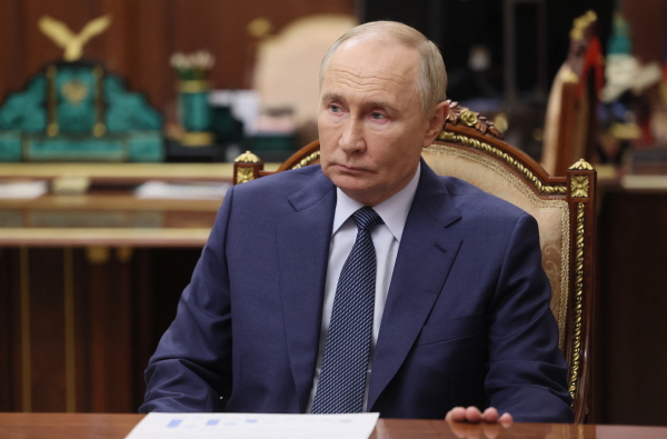 This photo shows Russian President Vladimir Putin seated on a chair. He's wearing a blue suit.