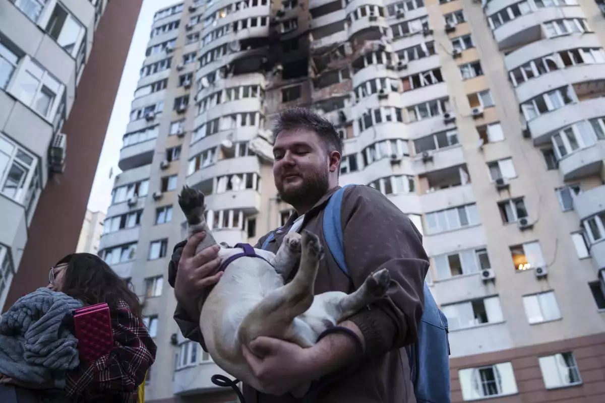 A man carries his dog in front of a residential multi-story building damaged after a Russian drone strike on Kyiv, Ukraine on Friday.