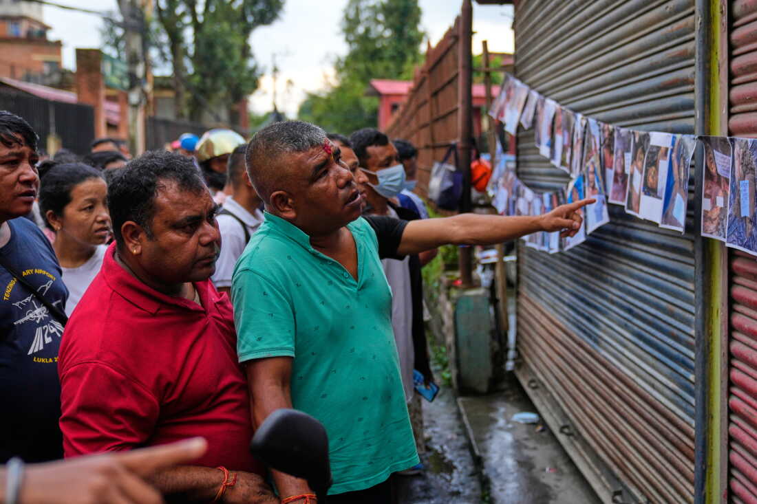 People look at photographs of people killed in flash floods displayed outside a government hospital to help relatives identify the victims in Kathmandu, Nepal.