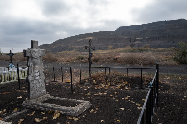 DOBROPILLYA, UKRAINE - OCTOBER 17, 2024 A slag heap from a nearby coal mine is seen from a cemetery at the edge of the mining town of Dobropillya, Ukraine on Thursday, October 17, 2024. The front line is nearby as Russian forces advance on Pokrovsk an important coal mining center about 14 kilometers southeast of Dobropillya. (Photo by Michael Robinson Chávez for National Public Radio)