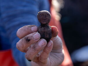 Charlotta Hillerdal holds up a wooden doll found in the soil at Nunalleq.