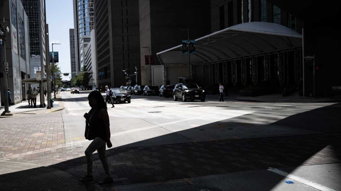 A woman walks in the shade in downtown Houston, Texas, on July 30, 2026, during a regional heat wave. A heat wave has hit Southeast Texas, with temperatures rising to near 100 degrees Fahrenheit (37 degrees Celsius).