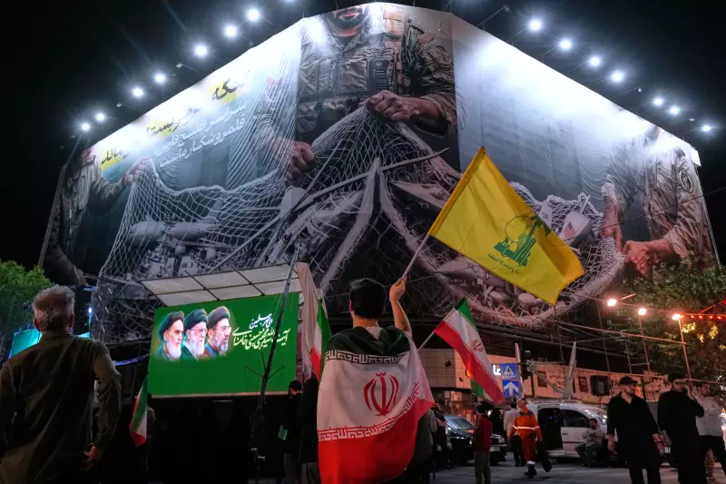 An Iranian demonstrator waves a flag of the Iran-backed Lebanese militant group Hezbollah under an anti-U.S. billboard, depicting the American aircrafts into the Iranian armed forces fishing net with signs that read in Farsi: "The Strait of Hormuz will remain closed, The entire Persian Gulf is our hunting ground," during a pro-government gathering at Enqelab-e-Eslami, or Islamic Revolution, square in Tehran, Iran, Monday.