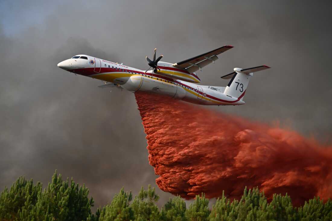 A plane releases fire retardant as it flies over a forest near Blagon, during wildfires in southwestern France, July 29, 2026.