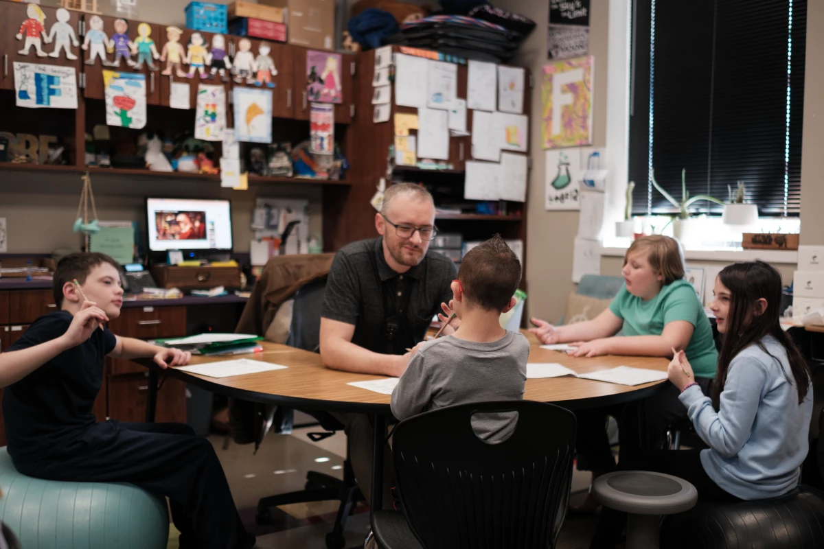 Kellen's homeroom teacher, Adam Frederick, works with Kellen and other students on a math lesson.
