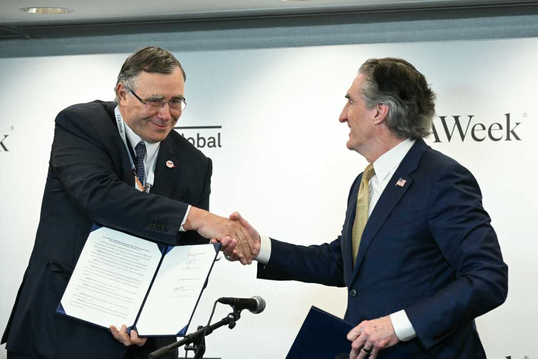 TotalEnergies CEO Patrick Pouyanné, left, shakes hands with Interior Secretary Doug Burgum after signing an agreement at an energy conference in Houston to end the French company's offshore wind projects in the U.S. and redirect those funds towards fossil fuel production.