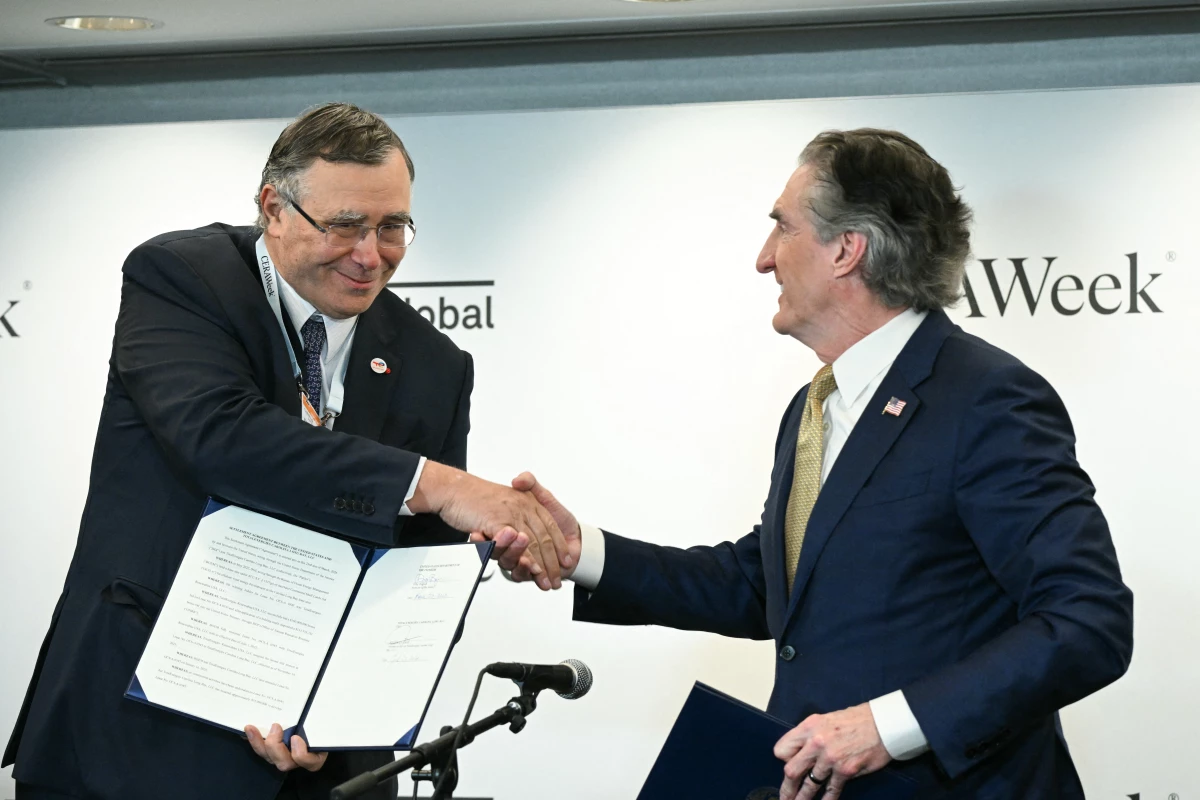 TotalEnergies CEO Patrick Pouyanné, left, shakes hands with Interior Secretary Doug Burgum after signing an agreement at an energy conference in Houston to end the French company's offshore wind projects in the U.S. and redirect those funds towards fossil fuel production.