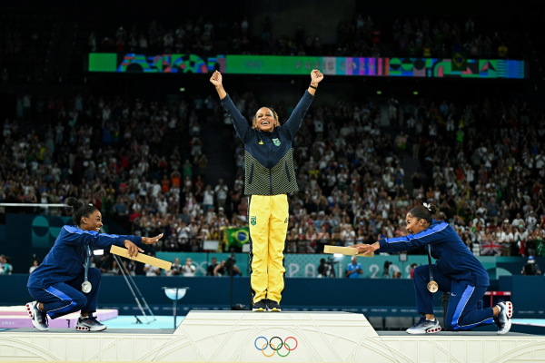 Simone Biles, left, joins teammate Jordan Chiles in pointing toward gold medalist Rebeca Andrade of Brazil. Biles won silver and Chiles bronze in the women's floor exercise at the Paris 2024 Olympic Games — the first time three Black athletes have shared the podium in Olympic gymnastics.