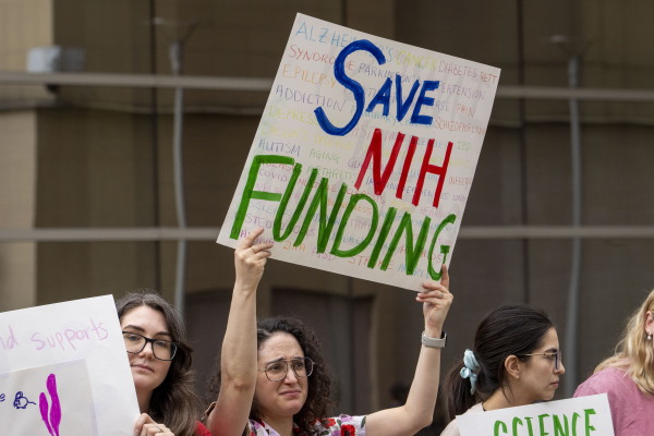 A protestor in Houston, Texas, holds a homemade sign that reads, "Save NIH Funding."