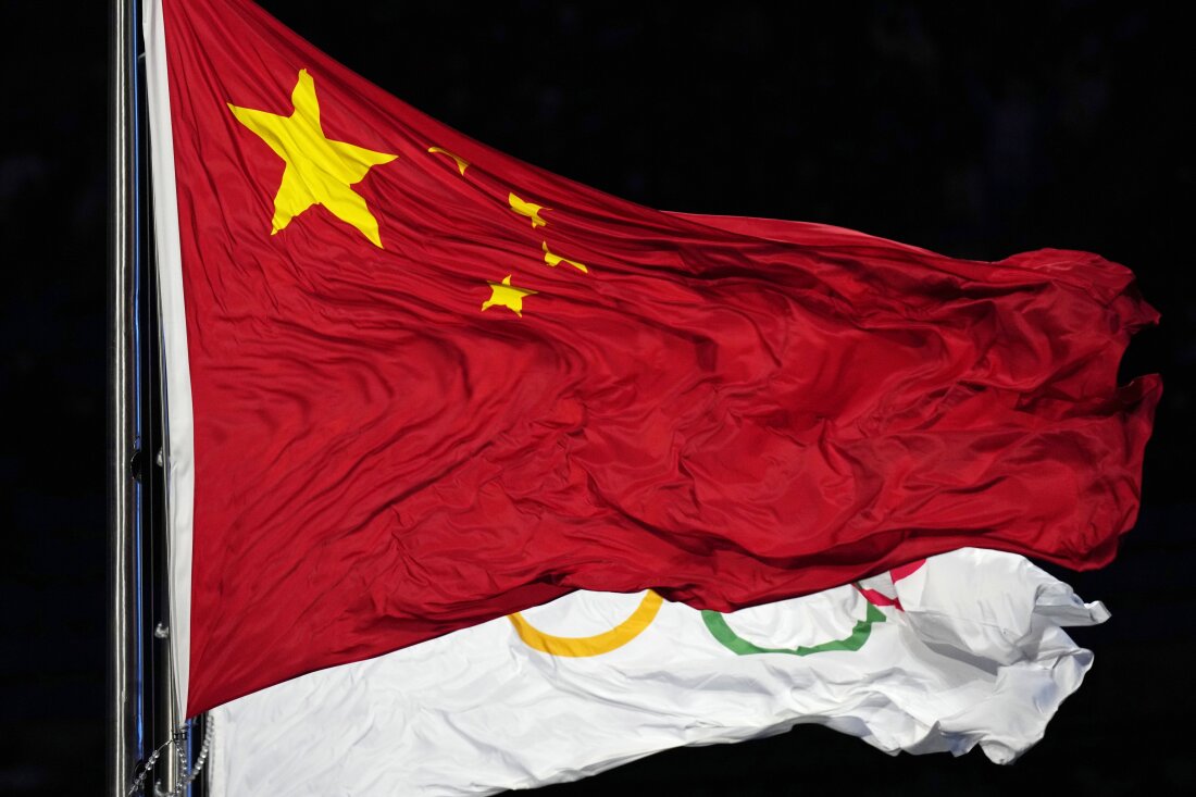 Warga Tiongkok dan bendera Olimpiade berkibar selama upacara pembukaan Olimpiade Musim Dingin 2022 di Beijing. Badan Antidoping Dunia membebaskan 23 perenang Tiongkok dari tuduhan doping meskipun hasil tes mereka positif menggunakan zat terlarang, sehingga mereka dapat bertanding di Olimpiade Tokyo 2021.