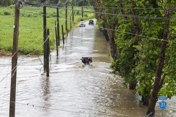 Vehicles try to navigate a flooded road in Naguabo, Puerto Rico, on Sunday, as Hurricane Erin brought heavy rain to the island over the weekend.
