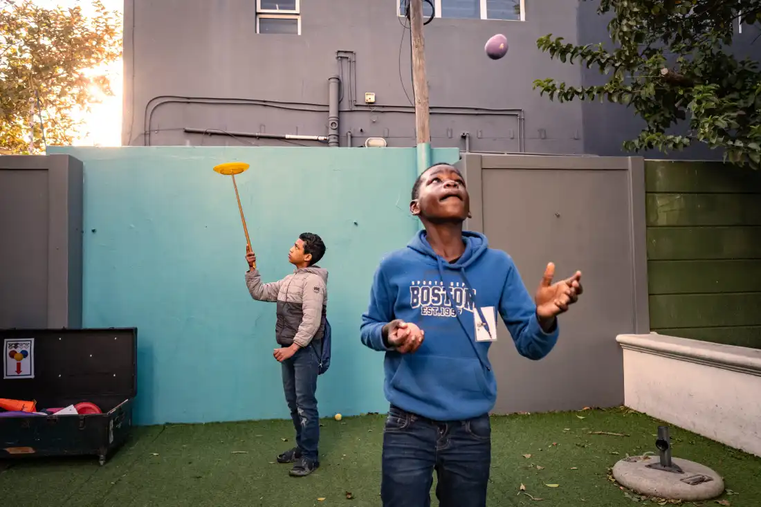 Students practice juggling and spinning plates before class at the Cape Town College of Magic.