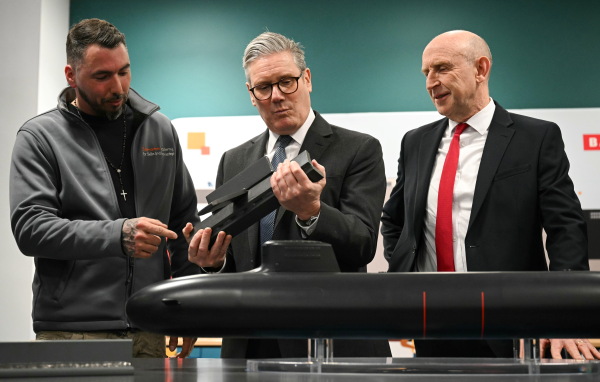 British Prime Minister Keir Starmer (center) and Britain's Defence Secretary John Healey (right) meet with BAE system apprentices as they look at a submarine model during a joint visit on March 20 in Barrow-in-Furness, United Kingdom. Starmer says the U.K. must upgrade its military in response to threats from Russia.