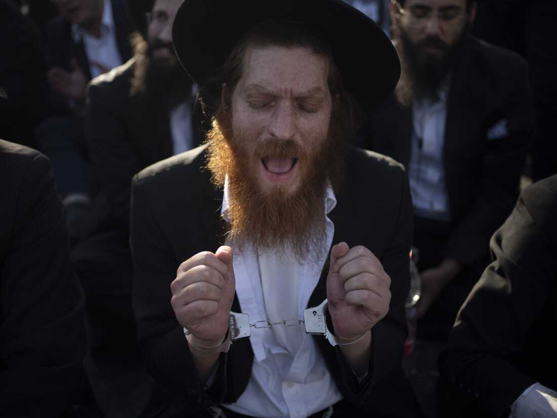 An Ultra-Orthodox Jewish man wears handcuffs as he sits on a street during a protest against army recruitment in Jerusalem on June 2.