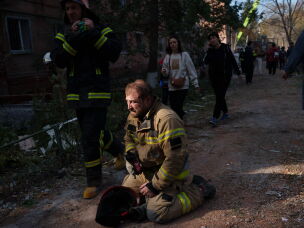 A rescue worker sits on the ground next to a residential building destroyed in a Russian missile strike on Pryluky, Ukraine, Wednesday.
