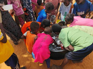Sudanese children scrape leftover food from an empty pot that was distributed in al-Rahmaniyah camp for displaced people, near the city of El-Obeid on July 7, 2026.