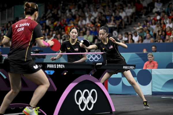 Rachel Sung and Amy Wang of the U.S. women's table tennis team take on Germany during the 2024 Olympic Games in Paris. at the South Paris Arena in Paris on August 6, 2024. (Photo by WANG Zhao / AFP) (Photo by WANG ZHAO/AFP via Getty Images)