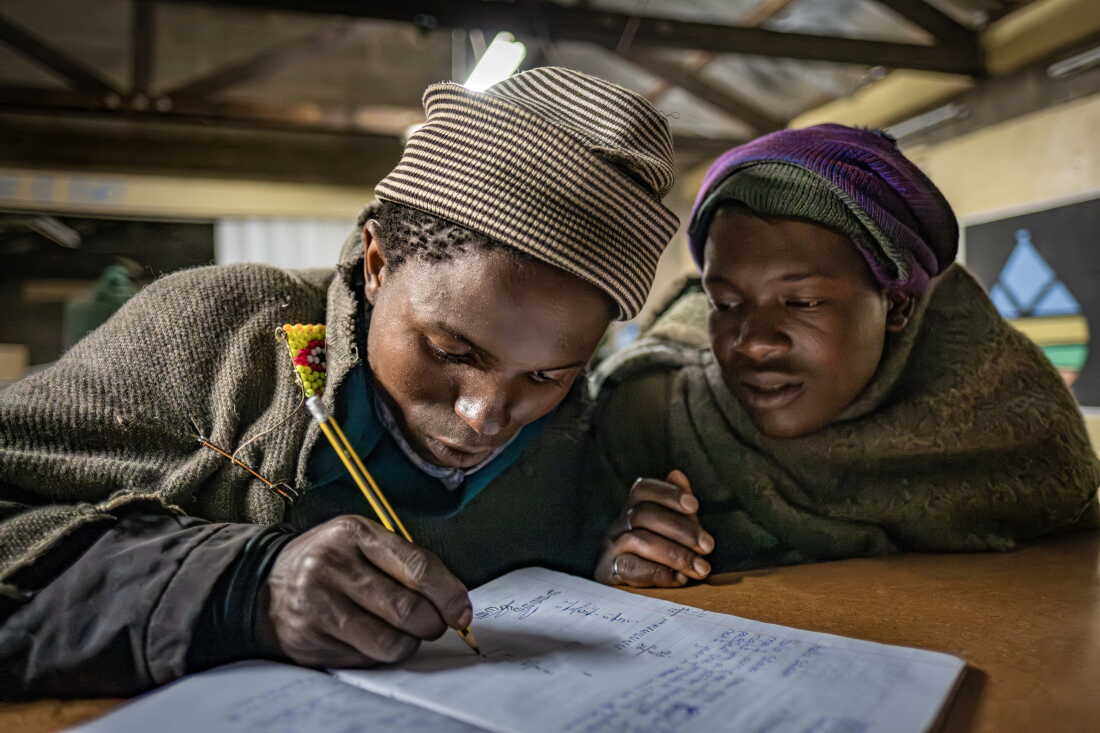 Shepherds Lepeli Maapesa, 23, (l) and Phakiso Phomane, 22, study in class at the Good Shepherd night school in Semonkong, Lesotho. Maapesa and Phomane both dropped out of formal schooling at a young age when they began working as herders. The Good Shepherd school is one of many night schools around the country striving to provide a basic education to the tens ofn thousands of shepherd boys and men who missed out on their schooling.