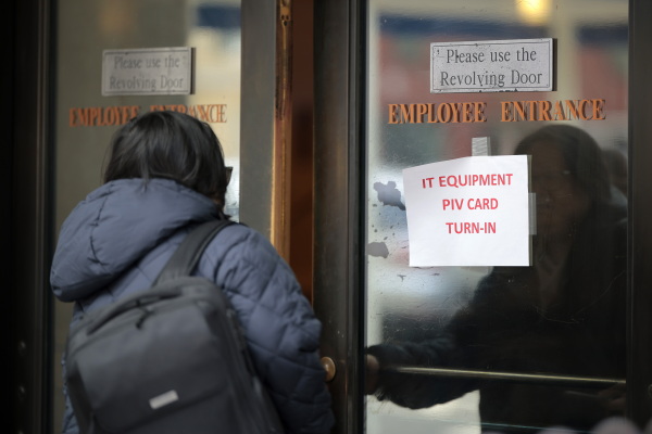 A person walks into the Department of Veterans Affairs' headquarters a block from the White House on March 6. A sign reads "Equipment PIV Card Turn In".