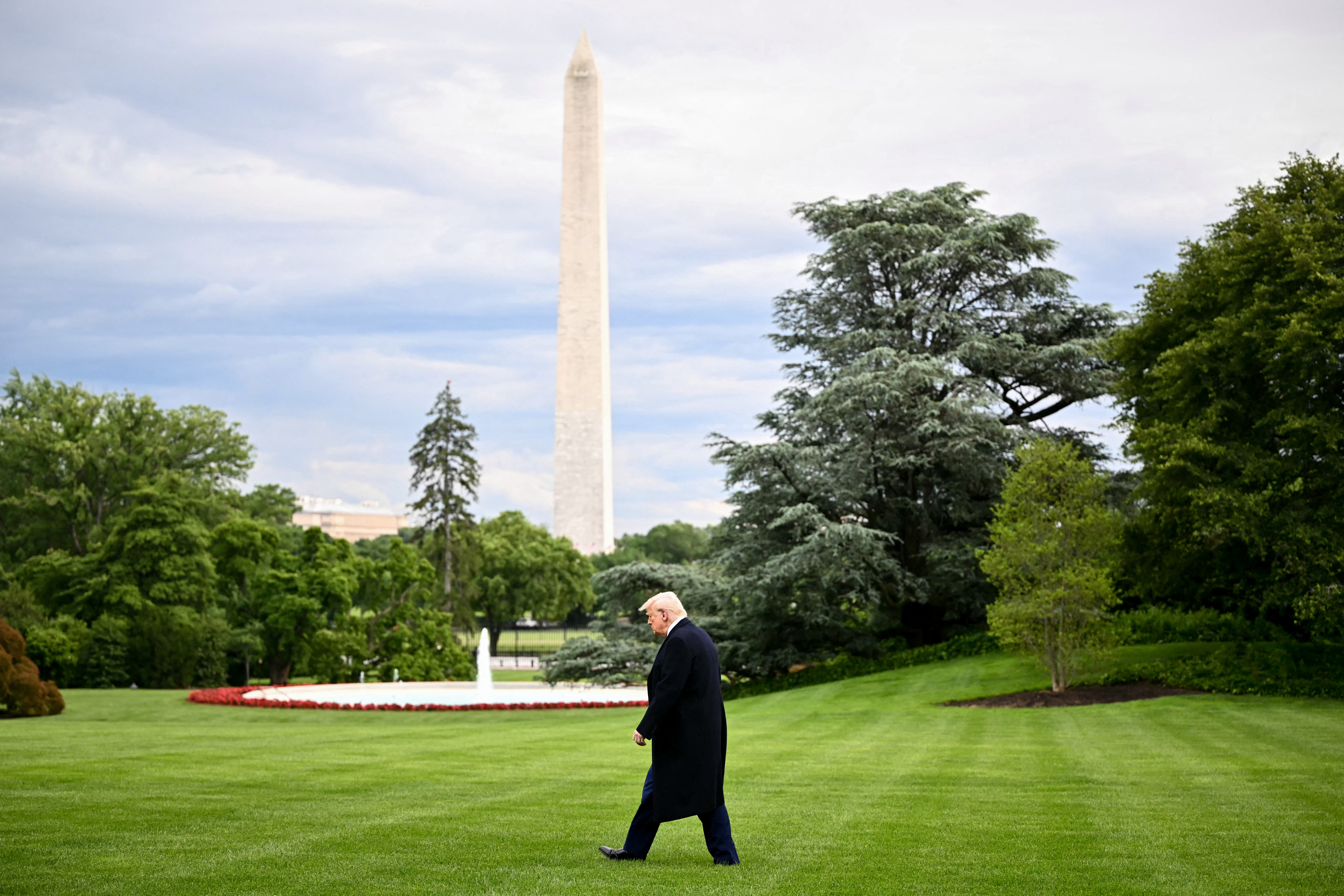 President Donald Trump is pictured walking to Marine One to depart the White House in May, with the Washington Monument in the background.