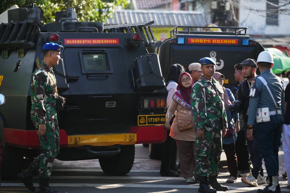 People look on as military personnel stand guard near a school where explosions reportedly occurred, in Jakarta, Indonesia, Friday.