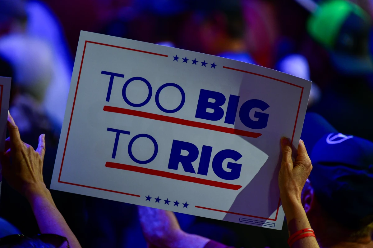 A supporter waves a sign reading 'Too Big to Rig,' a new campaign slogan from the Trump team focused on winning big enough margins to not lose - allowing the former president to repeat the lie that he won the 2020 election.