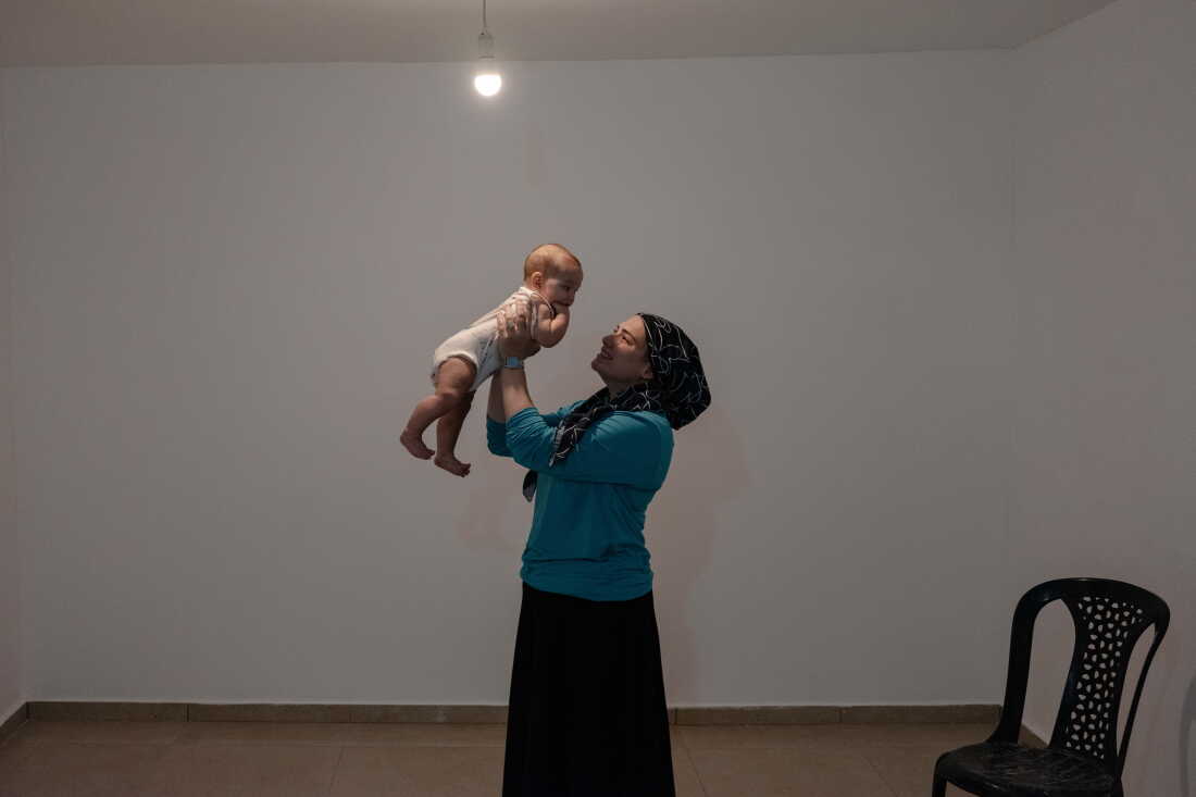 SDEROT, ISRAEL, SEPTEMBER 01, 2026: Robin Feldman, a new resident, with her baby inside her new apartment, which has not yet been furnished. Credit: Amit Elkayam for NPR.