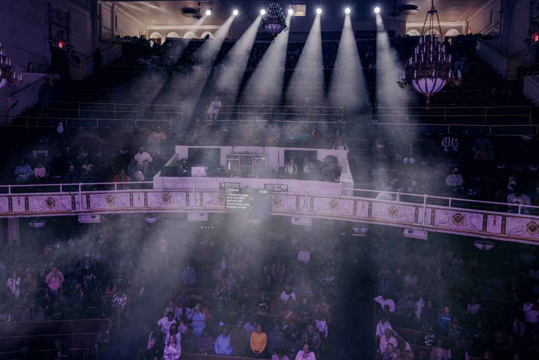 On the stage, a huge auditorium with a balcony is displayed in a wide -angle shot. Seven spotlights cast the light of light through the audience.