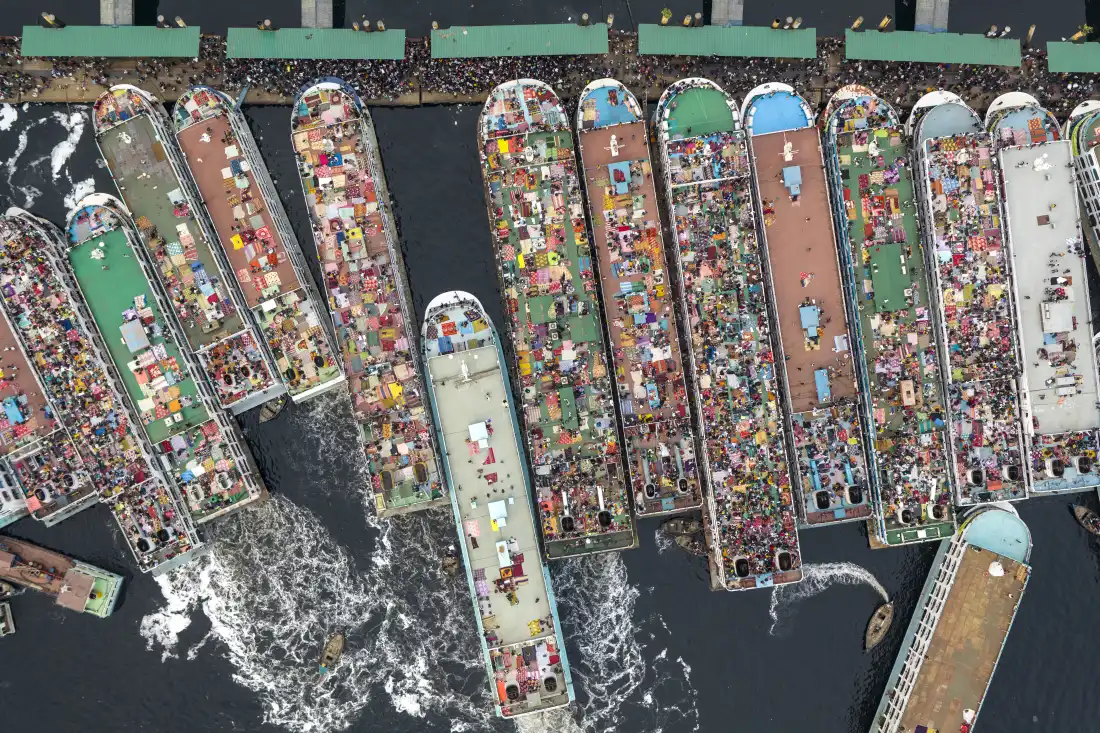 A crowd of homebound passengers is seen heading south from the Sadarghat Launch Terminal before the start of the Eid al-Fitr holiday on March 18, 2026. Although a new bridge was recently built across the Padma River, the rivers are still major passenger transportation routes. Due to rapid urbanization, the majority of people in Dhaka were born in rural areas, and go to their ancestral home for the weeklong holiday. Nearly 10 million people across the country have begun leaving cities to celebrate the festival with their families, creating heavy congestion and a festive atmosphere at all transport hubs.