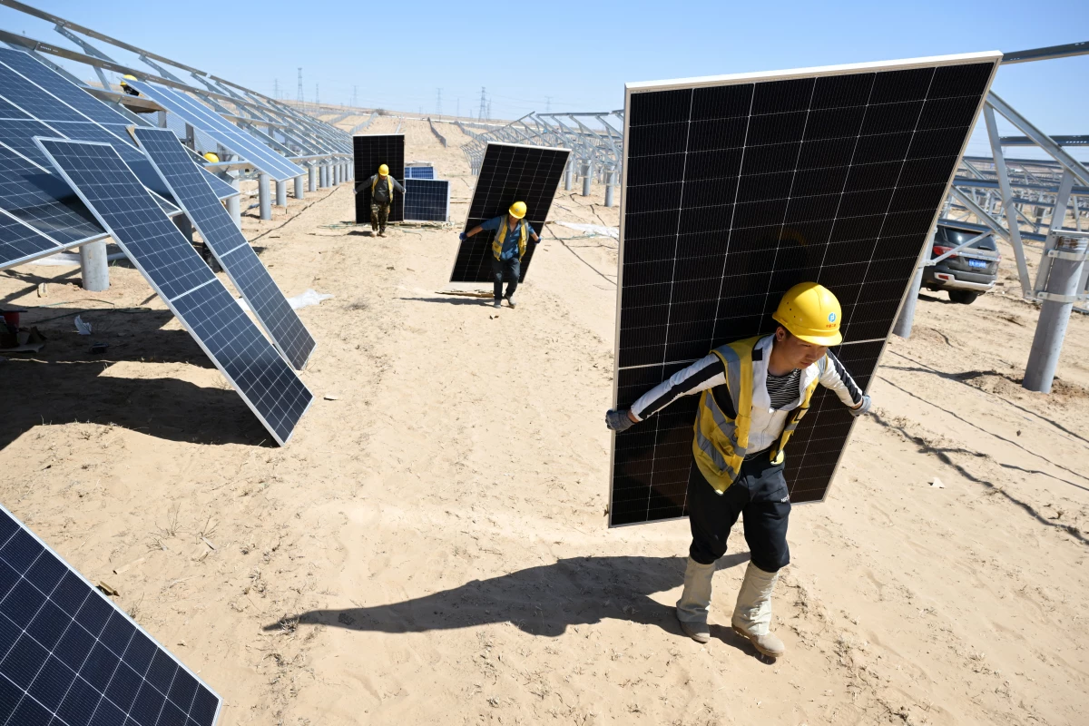 Workers carry solar panels this spring to be installed in the desert in China's northern Ningxia region. China is the world's biggest producer of green technology, like solar panels and electric vehicles.