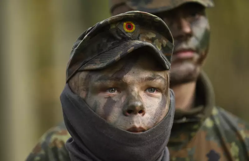 Two German recruits, wearing camouflage face paint and camouflage-print uniforms, attend a tank destruction exercise at the Westfalen-Kaserne barracks of the German armed forces on November 13, 2025. They are photographed from about the shoulders up.