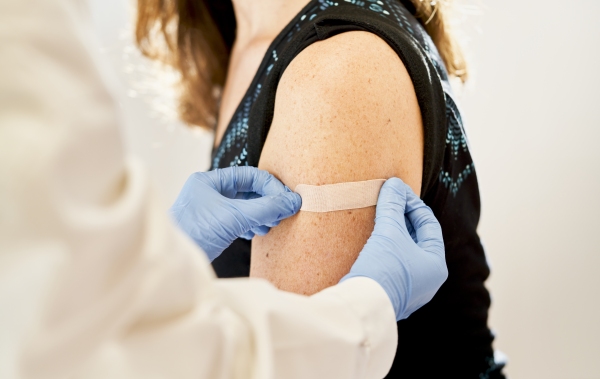 Doctor applying a bandage a patient's arm after an immunization.