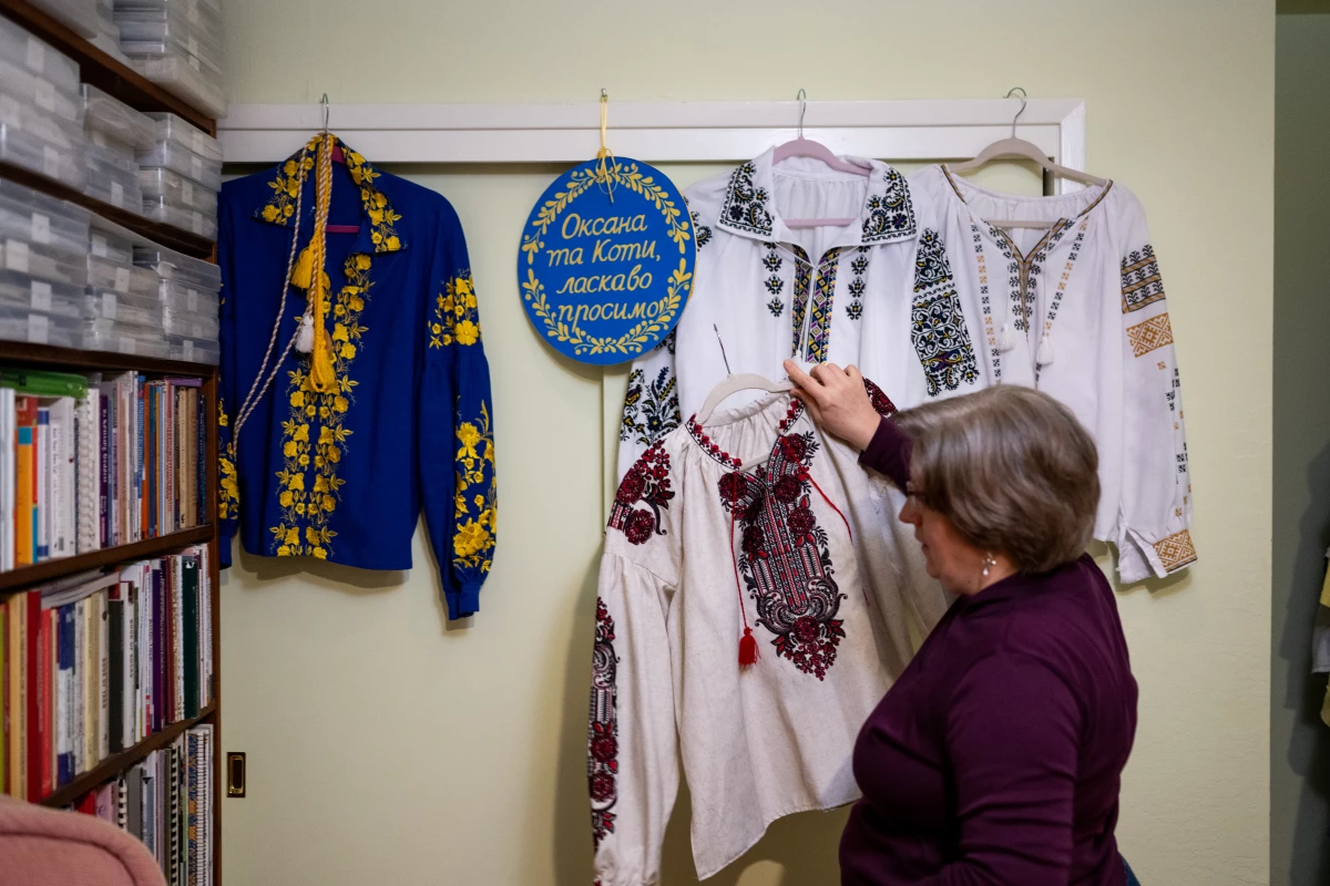 Oksana Demidenko hangs traditional Ukrainian embroidered shirts above her closet at her home. Hanging from the closet is a sign made by her sponsor, Mary Wogec, welcoming her and her cats to the United States.