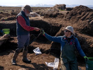 Principal archaeologist Rick Knecht examines an artifact found by volunteer excavator John Rundall.