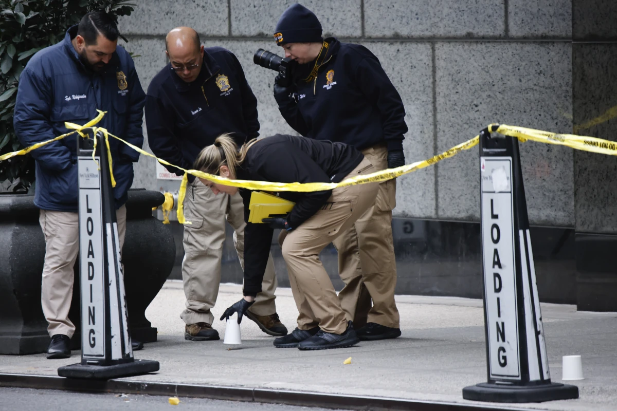 Members of the New York police crime scene unit pick up cups marking the spots where bullets lie as they investigate the scene outside the Hilton Hotel in midtown Manhattan where UnitedHealthcare CEO Brian Thompson was fatally shot on Dec. 4.